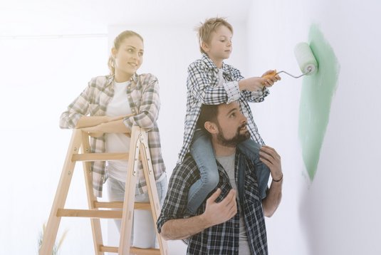 Familie beim Wandstreichen Ein Bild einer Familie, die eine Wand streicht.