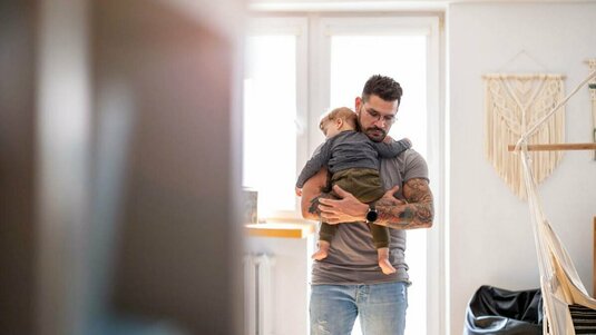 Vater mit seinem schlafenden Sohn auf den Armen